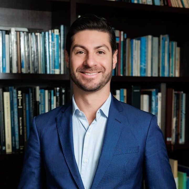 Claudio Marcelo Rodrigues Iarema, advogado, de blazer azul diante de uma estante de livros